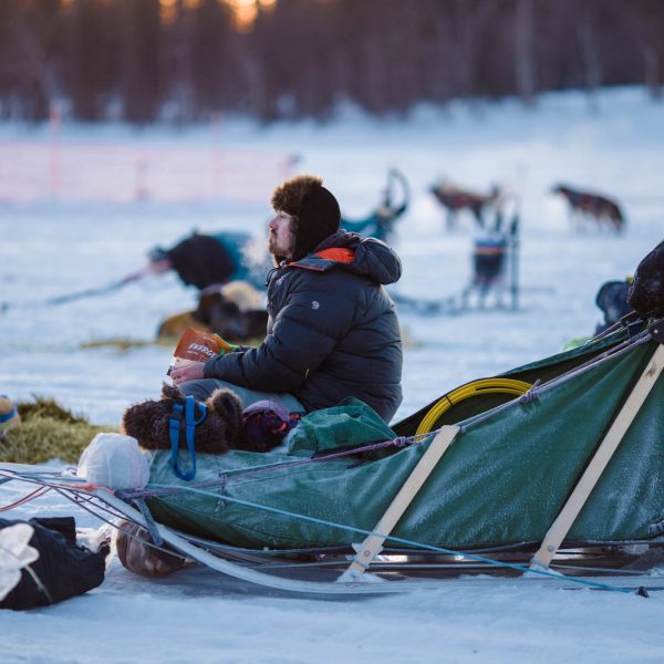 Musher eats while his dogs rest.