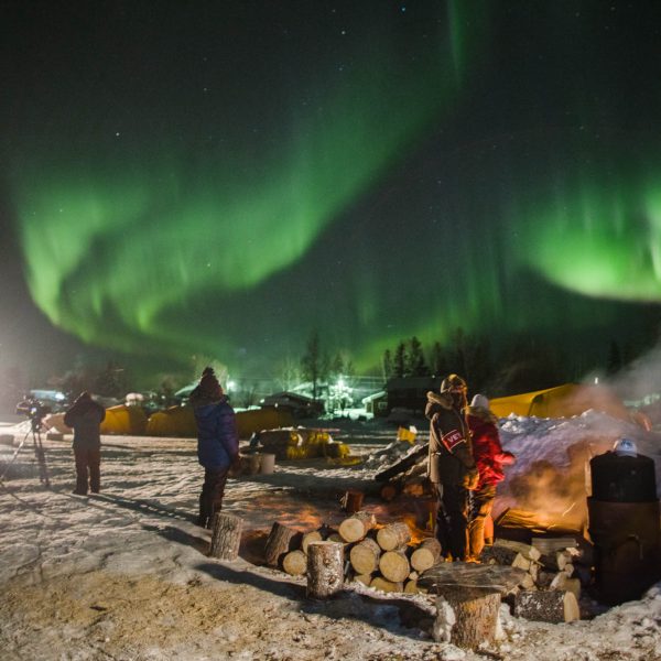 The aurora borealis shine bright over Nikolai as camera crew, volunteers, and locals wait for Dallas Seavey to arrive. The northern lights were so bright that this photograph was captured handheld at 1/6th second.