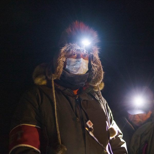 Race volunteer battles frost from his breath while checking in mushers.