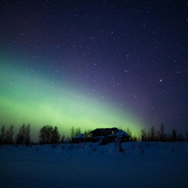 Iditarod ghost town ruins silhouetted by the northern lights.