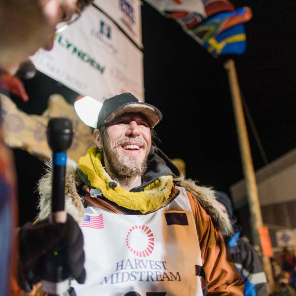 The 50th Iditarod champion Brent Sass being interviewed under the Burled Arch in Nome.
