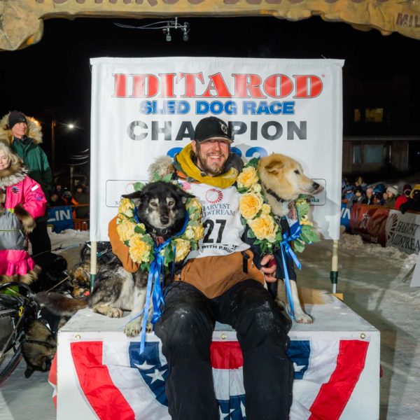 Iditarod 2022 champion Brent Sass with his lead dogs at the winners podium.